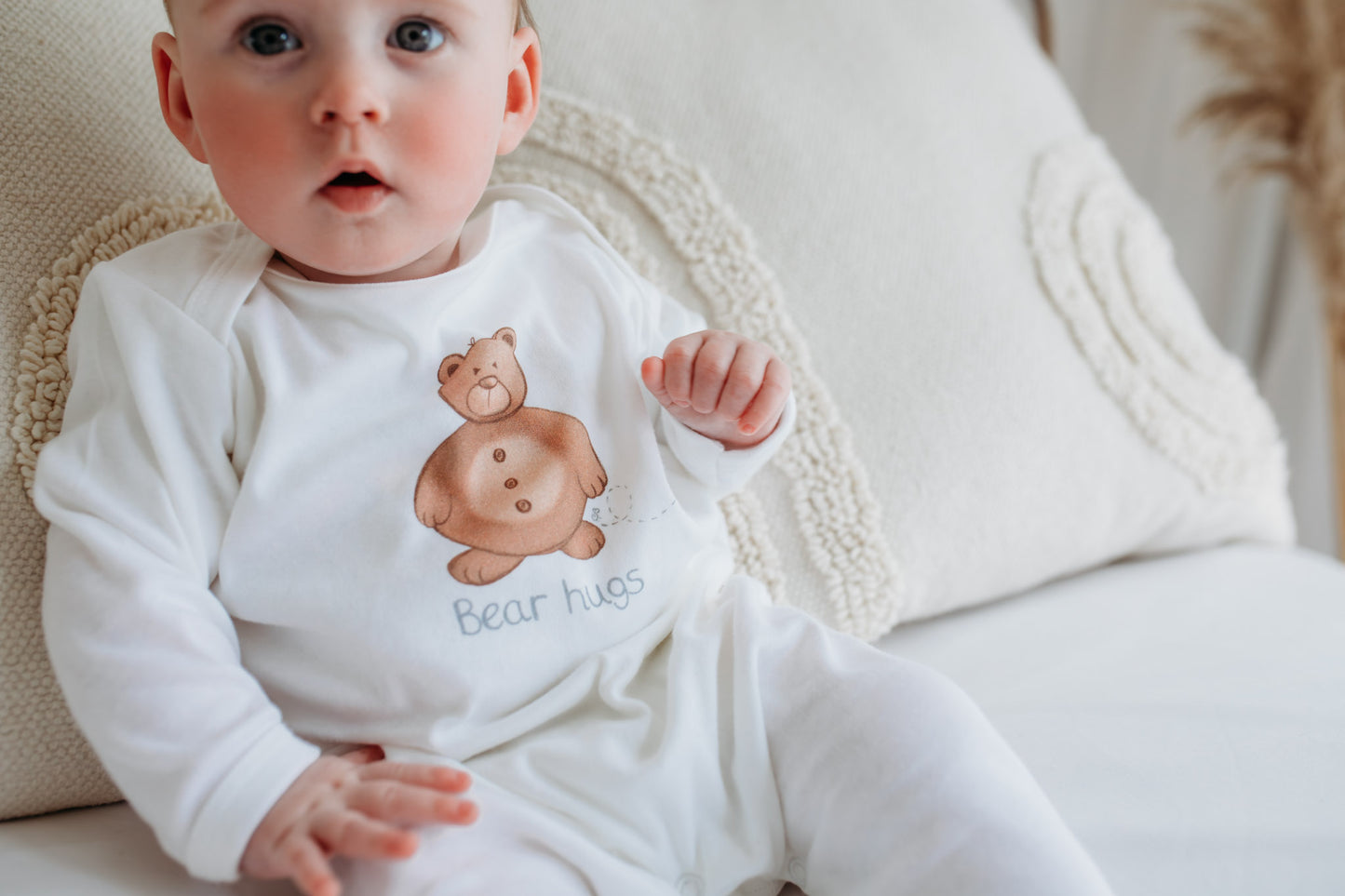 new baby boy wearing a woodland bear sleepsuit on a feeding chair