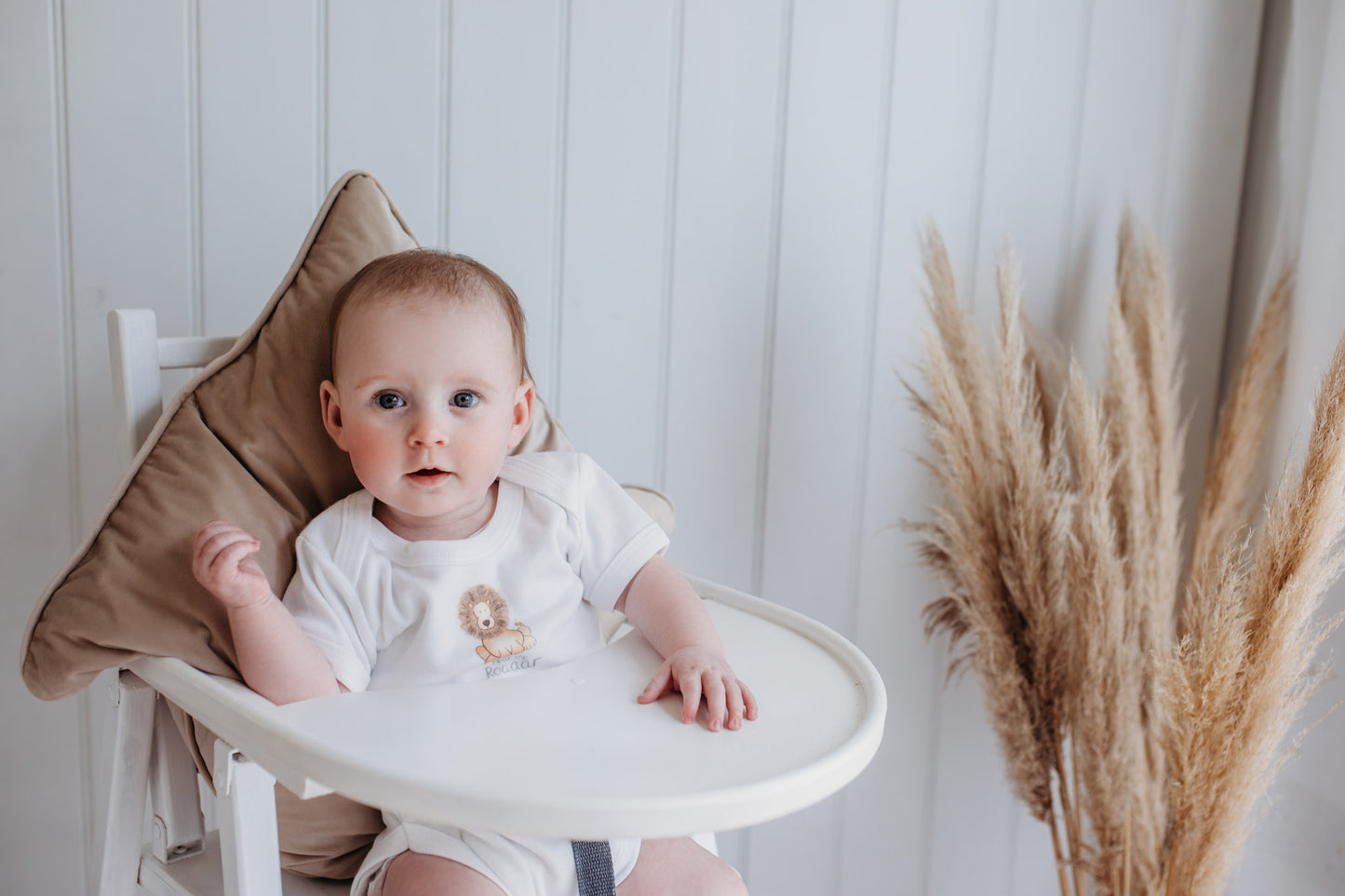 cute baby girl in a high chair wearing a bodysuit with a safari lion "hear me roar" print