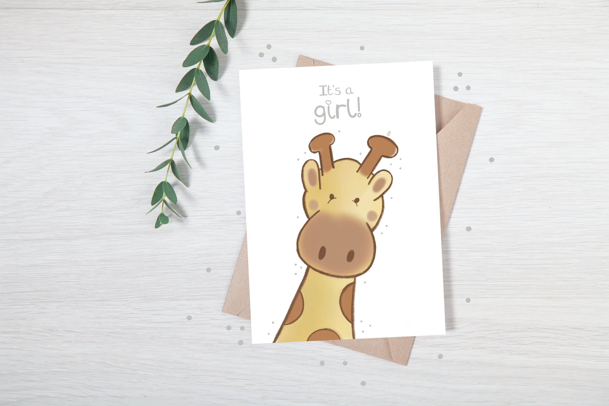 Handmade luxury new baby girl greetings card with a safari theme baby giraffe popping up from the bottom with the title &quote "it's a girl" on a white background, with a kraft envelope