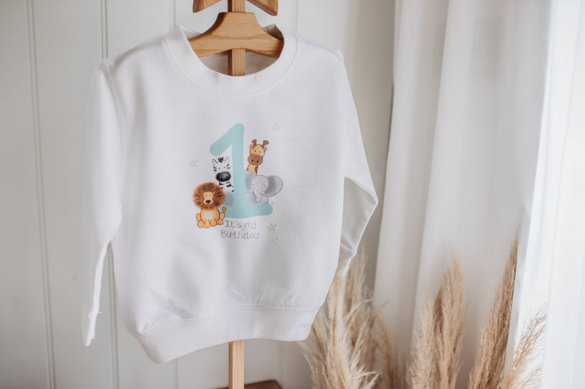 kids clothes stand holding a "it's my birthday" printed 1st birthday sweatshirt woth jungle safari animal design for boy girls birthday party