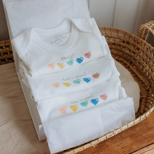 set of 3 love heart printed baby bodysuits in mixed sizes with "hello" "Let's Play" and "Bee Happy" quotes in a luxury gift box