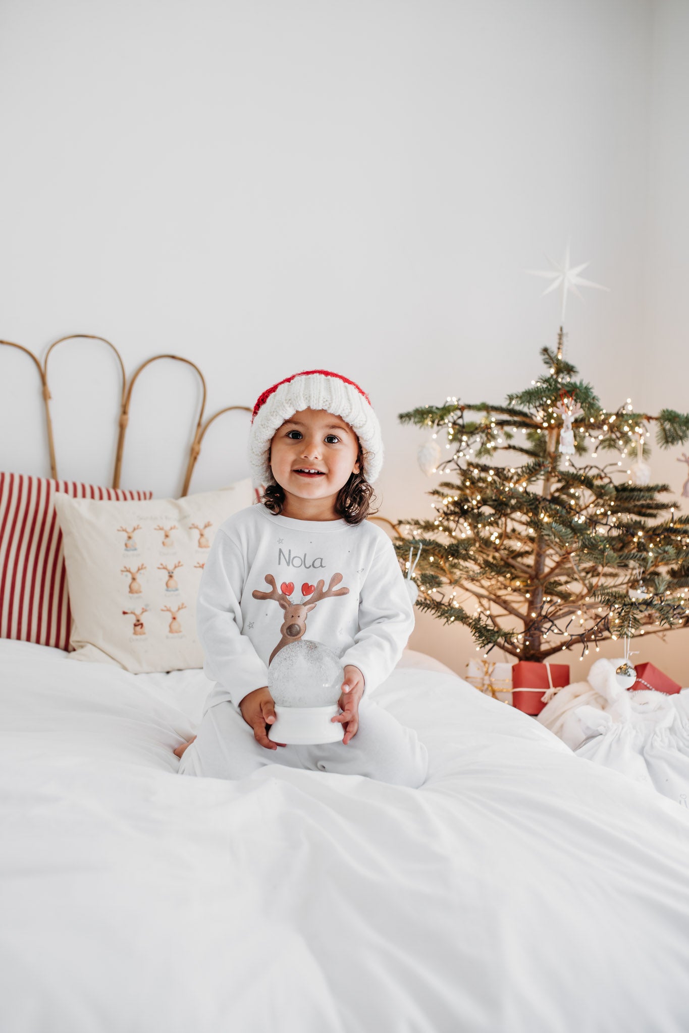 girls holding a snow globe wearing a santa hat and personalised christmas pyjamas