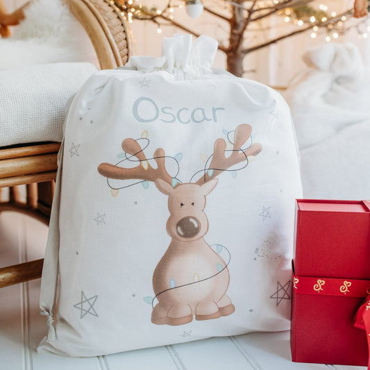 personalised reindeer christmas sack under a christmas tree filled with presents