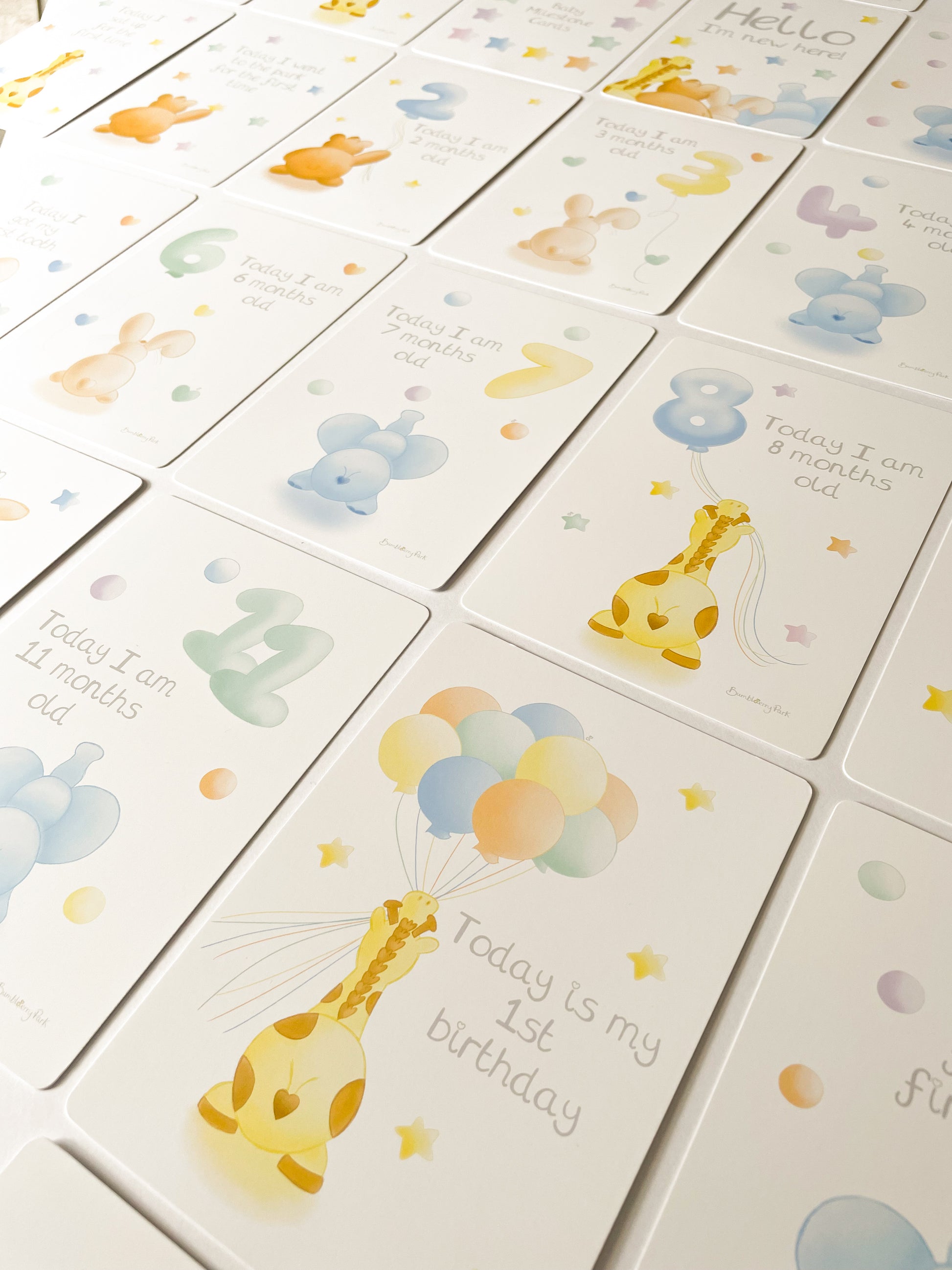 flat lay of pastel animal theme baby milestone cards with numbered balloons for milestone moments