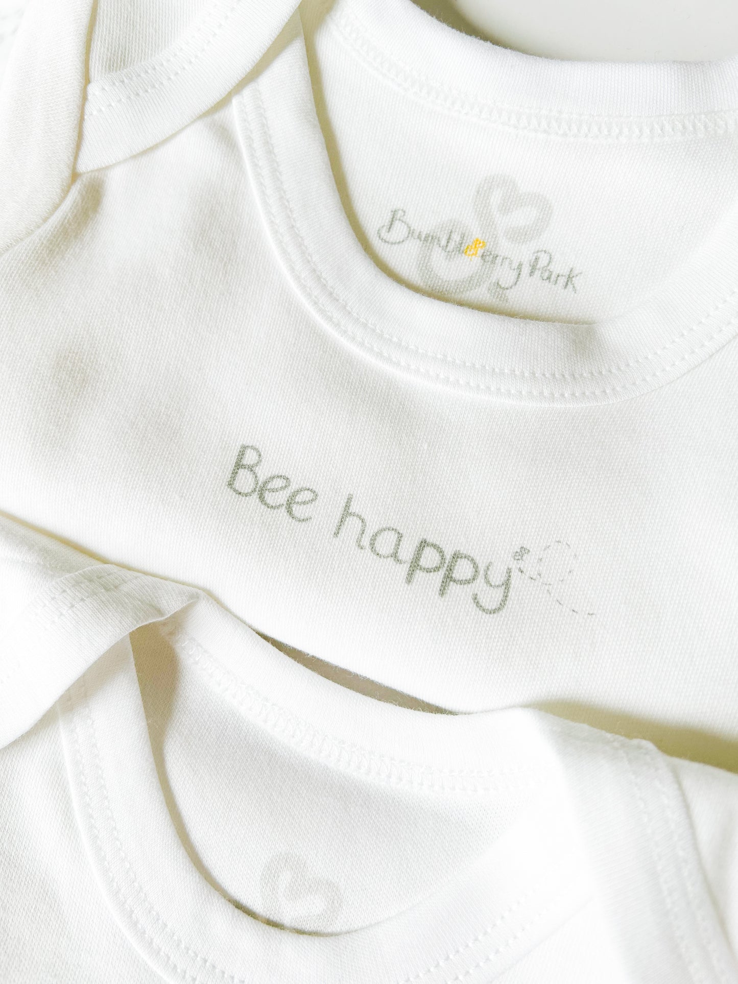 bee happy text design on white baby babygrow