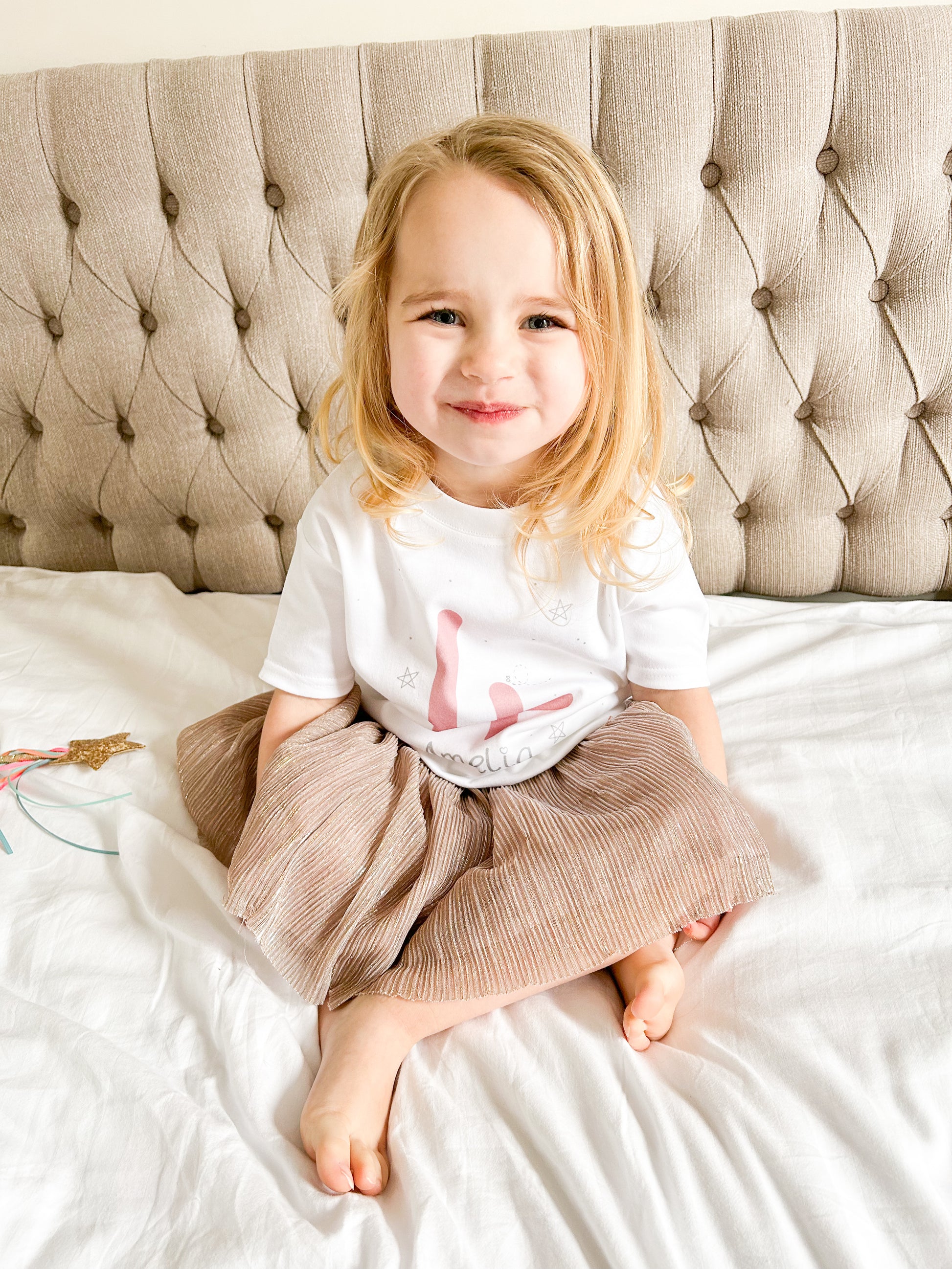 girl sat on a bed wearing a pink party outfit