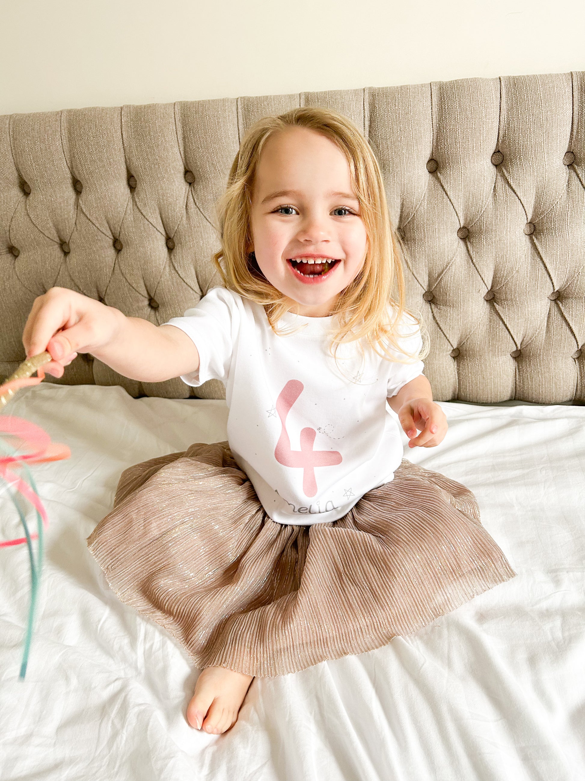 girl pointing at the camera with a magic wand wearing a 4th birthday top and pink tutu