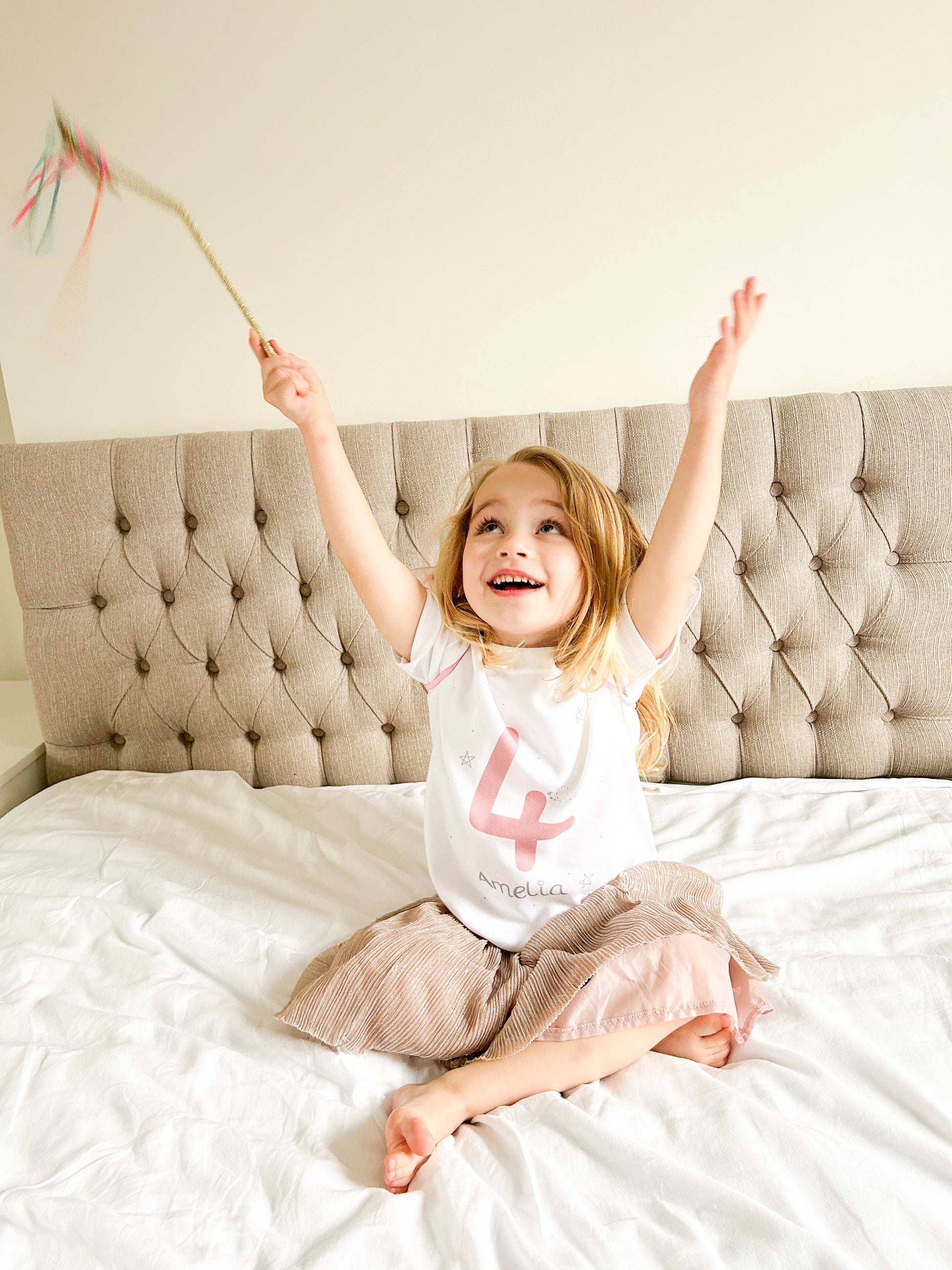 girl reaching for the stars holding a magic wand and personalised 4th birthday party outfit and sparkly skirt