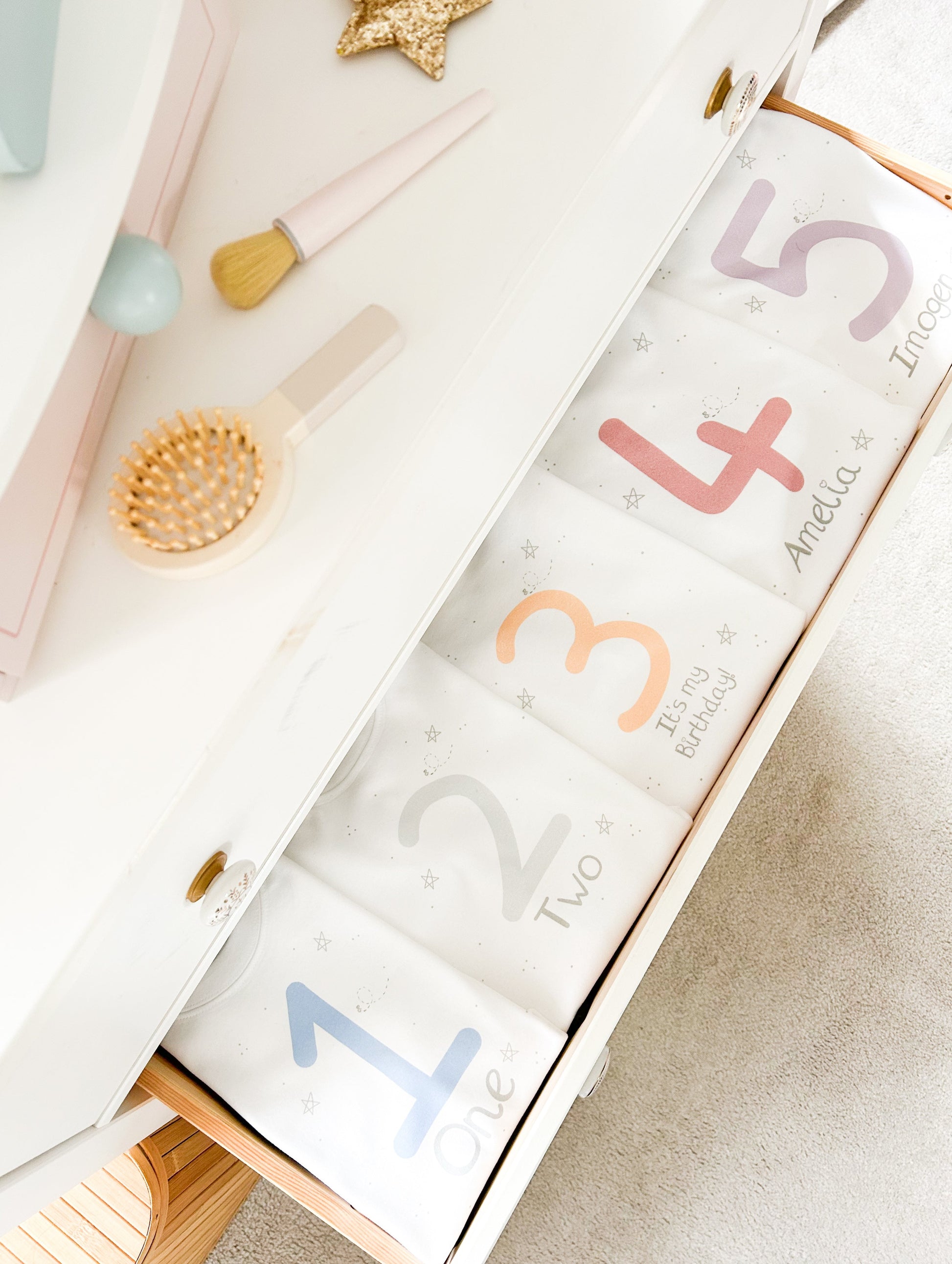 toddler bedroom drawers open with personalised birthday t-shirts and sweatshirts inside printed with names and ages in bright pastel colours