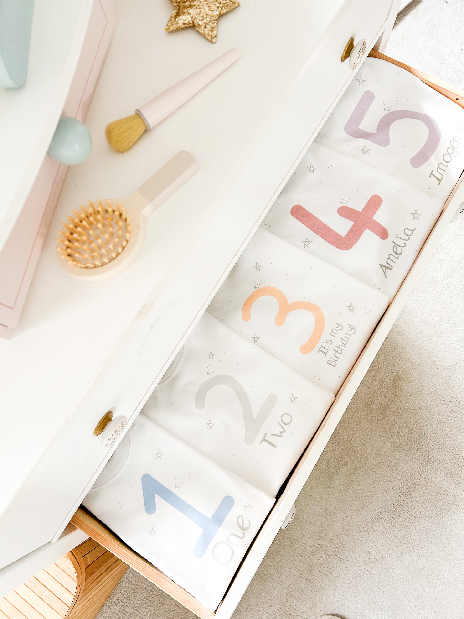 boys bedroom drawers open with custom birthday t-shirts inside with "it's my birthday" print and ages and names in muted blue, grey, peach, red and purple colours