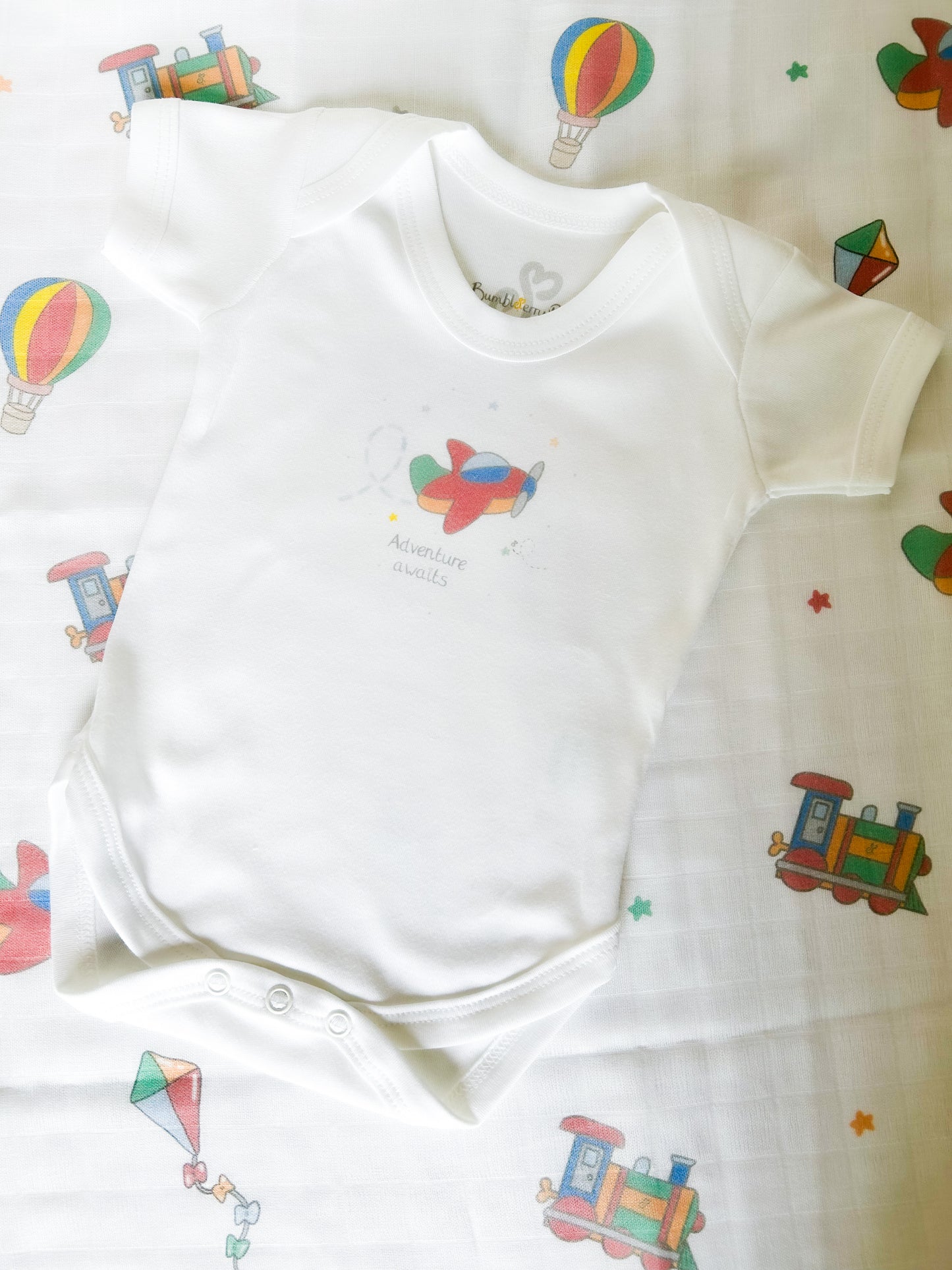 gift set of baby bodysuit and muslin cloth with travel and transport theme print in bright primary colours