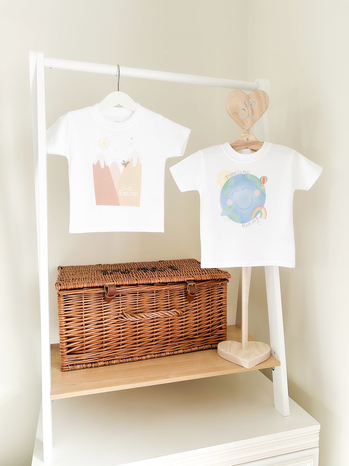 two children's t-shirts with go explore and planet earth neutral prints with the world, and mountains in muted colours