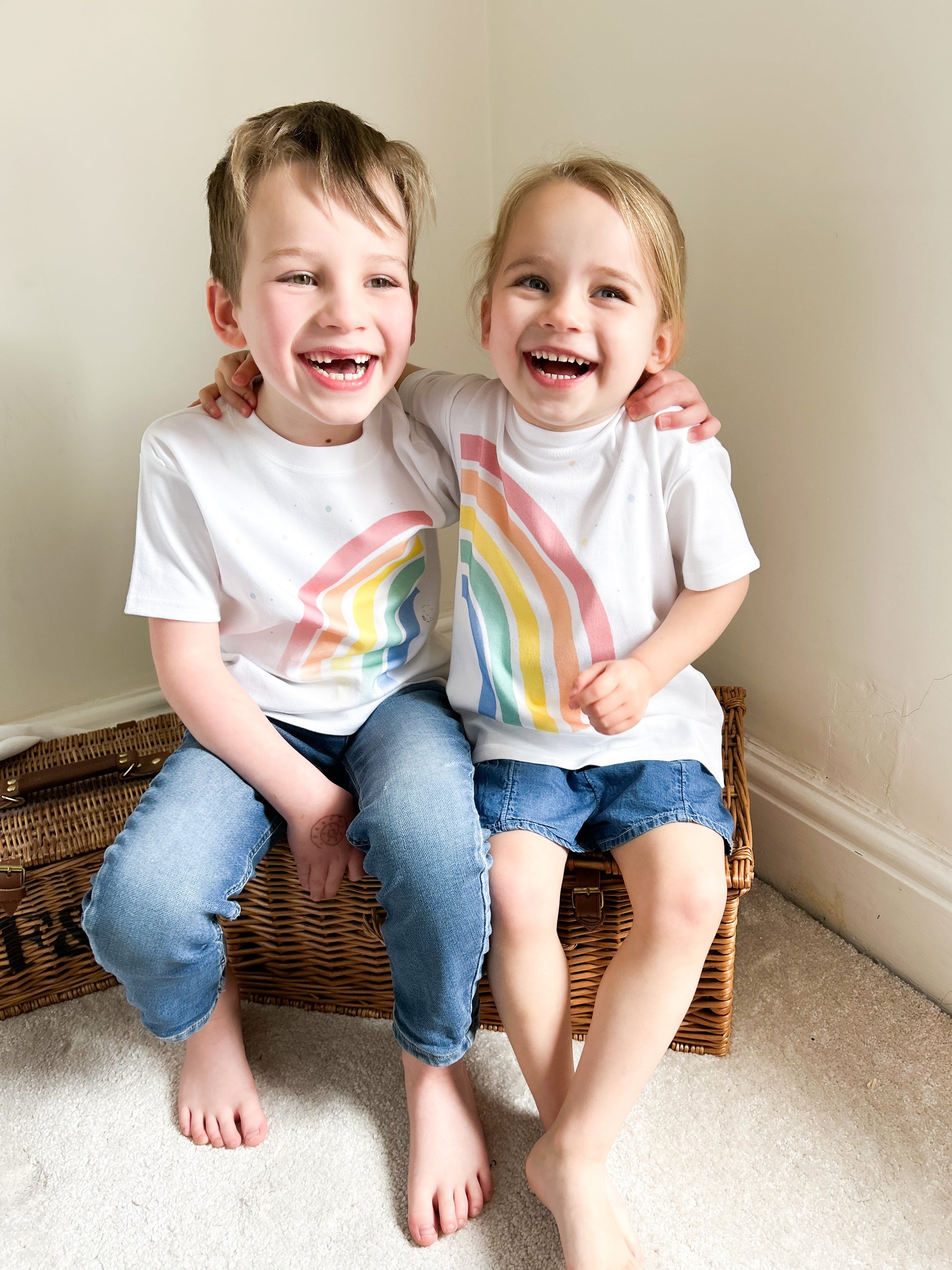 boy and girl hugging wearing a bright matching rainbow t-shirts